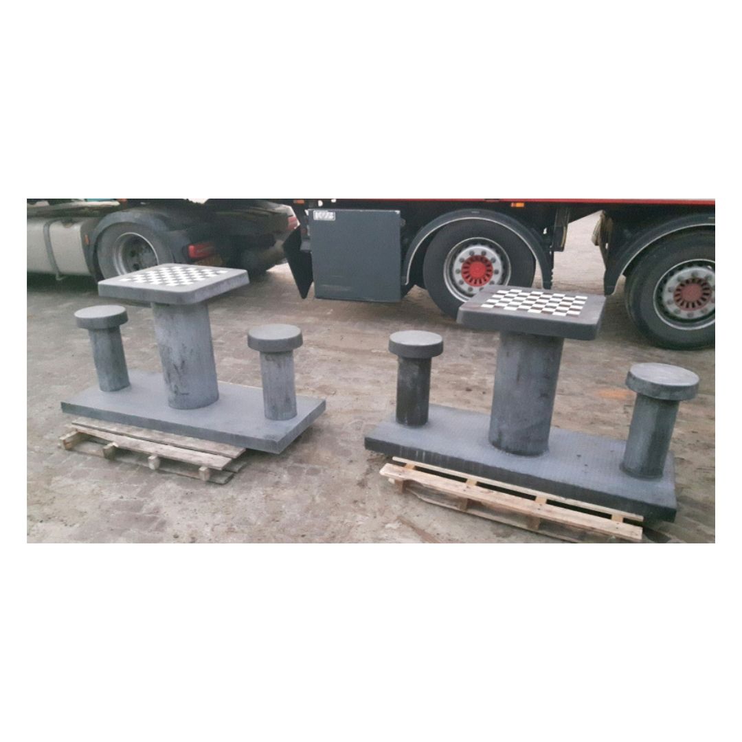 Skakbord i beton til to personer stående ved siden af hinanden på paller foran en stor lastbil